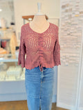 red crochet top on a mannequin with blue jeans in a store setting