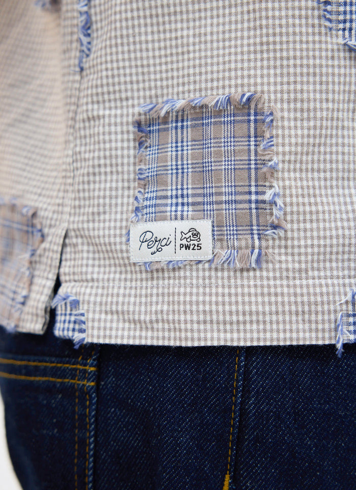 Close-up of the Percival Bruno Boxy Clerk Shirt in grey, showing the frayed patchwork detail and Perci PW25 woven brand tab.