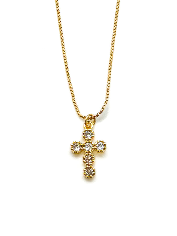 Gold cross necklace with clear stones on a white background