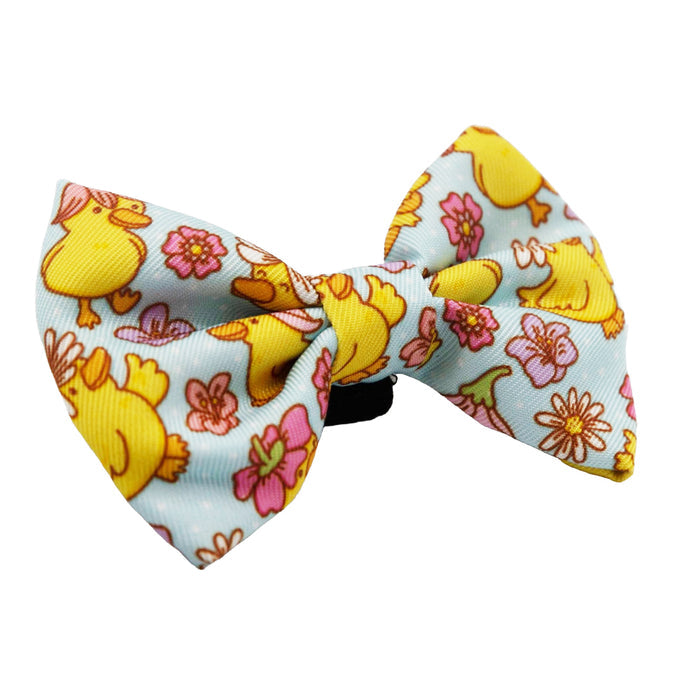 The Cat Bowtie - Good Duck, Babe! by Sassy Woof features a light blue fabric with yellow cartoon ducks and vibrant pink and orange flowers for a playful touch.