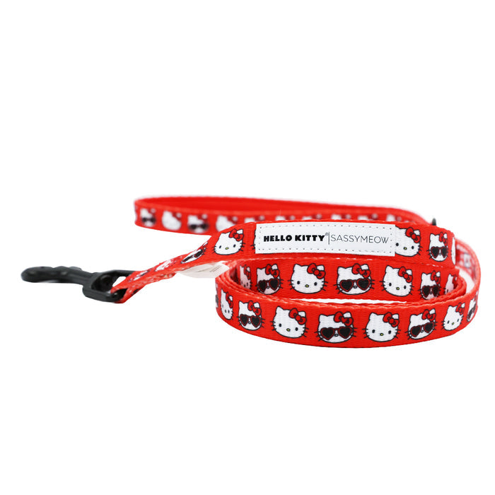 The Cat Leash - Hello Kitty® Red Classic by Sassy Woof features a repeating Hello Kitty face pattern, comfy neoprene handle, black metal clasp, and a white label that reads HELLO KITTY | SASSYMEOW.