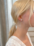 Close-up of woman wearing light blue clover stud earrings with gold trim