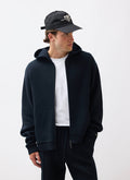 A model wears the black Percival Chronicle Knitted Hoodie, open over a white t-shirt, against a white studio background.