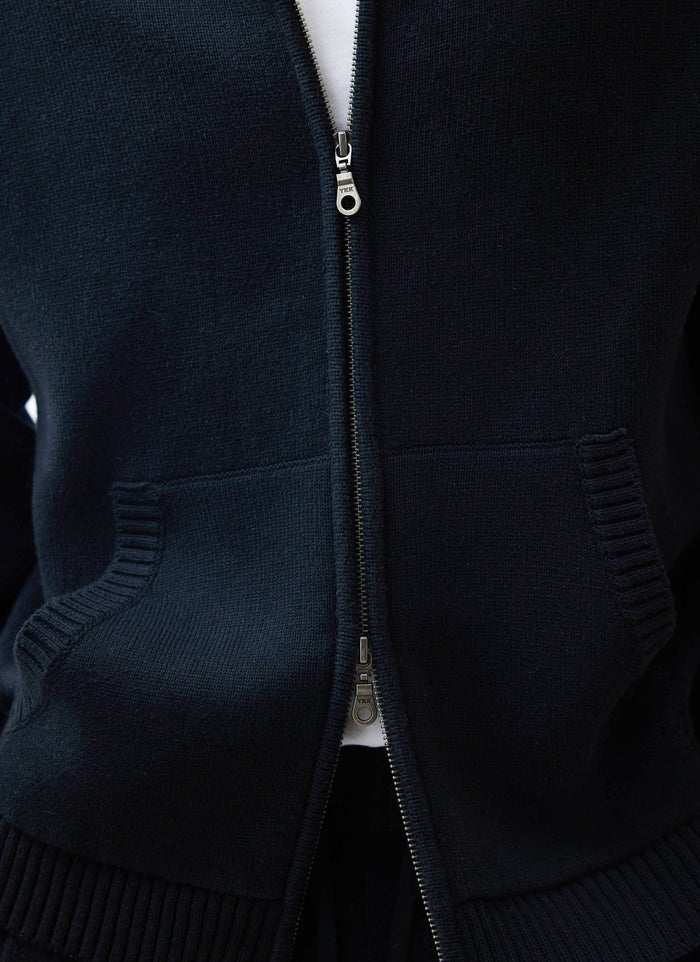 Close up of the Percival Chronicle Knitted Hoodie in black, showing the two-way zip and tight cotton knit.