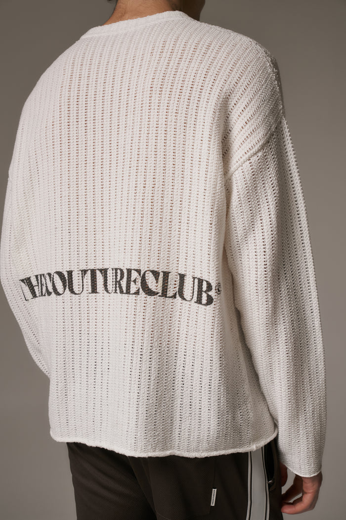 Person wearing a white crochet knit long sleeved t-shirt with branded text on the back against a neutral background.