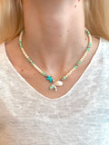 Coralie Charm Necklace with seafoam beads and coastal charms on models neck