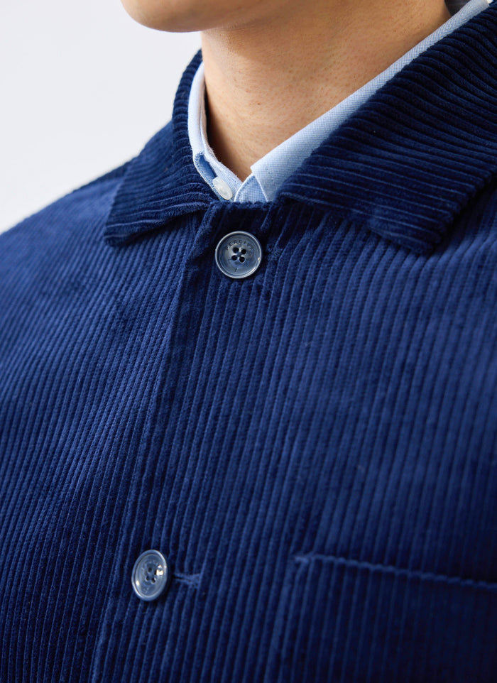 A close-up of the Percival Cord Overshirt in navy, showing the heavyweight corduroy texture and a branded button.