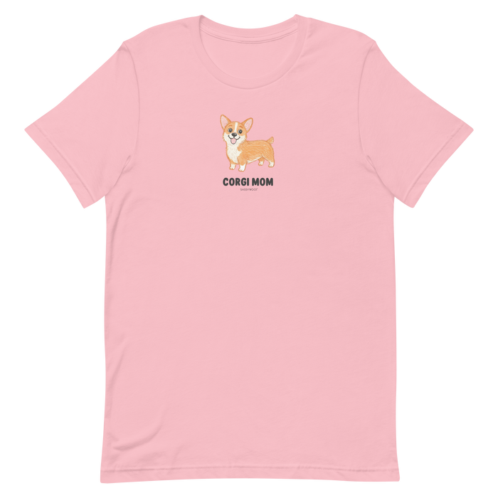 Sassy Woof's Corgi Mom Tee is a light pink shirt featuring a cute cartoon corgi with "CORGI MOM" text centered below the illustration—a perfect choice for fans of this adorable breed.