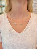 Necklace with small floral pendants worn by a person in a light-colored top.