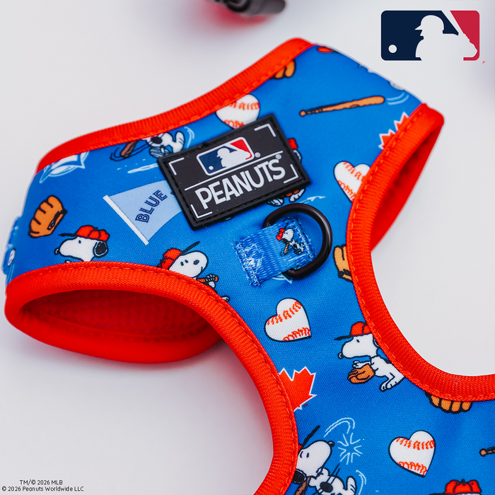 The Sassy Woof Dog Adjustable Harness - MLB™ x Peanuts™ Toronto Blue Jays™ features Snoopy, baseballs, bats, and gloves on a white background with blue and red trim, plus Peanuts and Major League Baseball logos.
