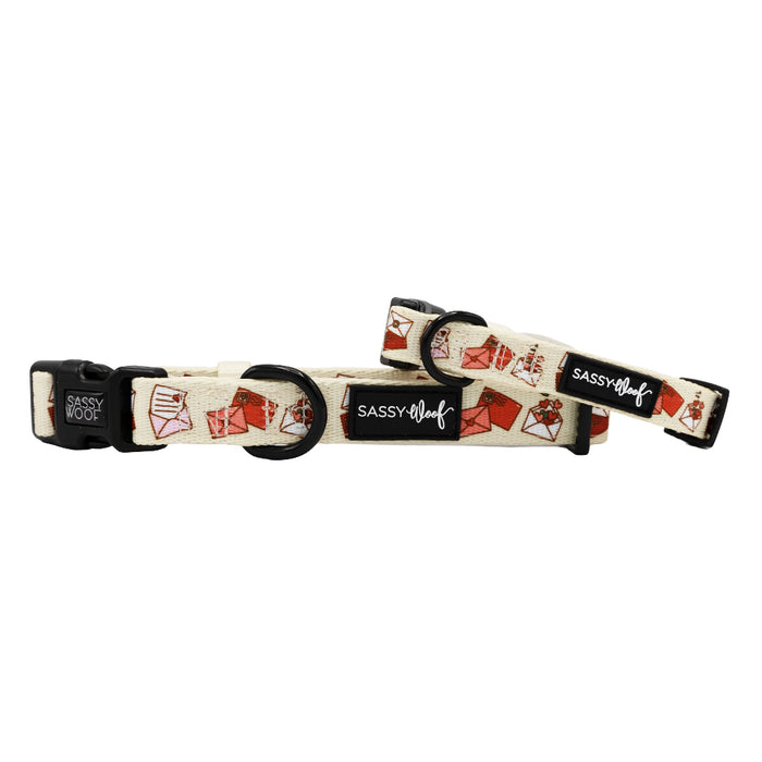 The Sassy Woof Dog Collar - P.S. I Woof You is a beige adjustable collar with black hardware, decorated with red and brown takeout food prints and two black Sassy Woof labels—a playful touch for your pup's collection.