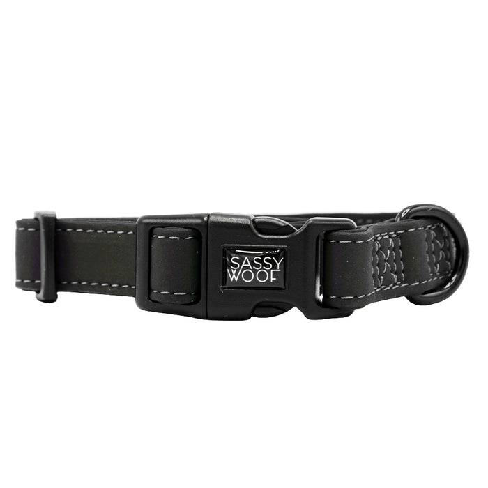 The Sassy Woof Dog Collar - Reflection is a black adjustable collar with white stitching, a plastic Sassy Woof buckle, metal D-ring for leash attachment, and reflective design for enhanced nighttime safety.