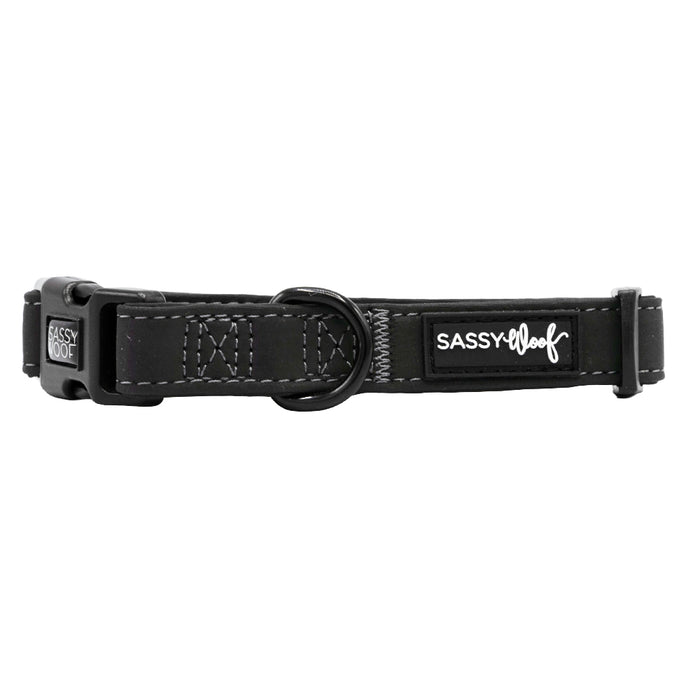 The Sassy Woof Dog Collar - Reflection is a black adjustable collar with white stitching, a plastic buckle, metal ring, and reflective design for nighttime safety.