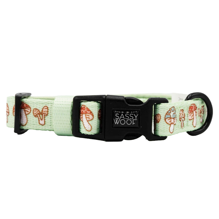 The Sassy Woof Dog Collar - Shrooms & Blooms is a light green adjustable neoprene collar with a black plastic buckle, a Sassy Woof label, and a playful small brown mushroom pattern—perfect comfort and style for your pup.