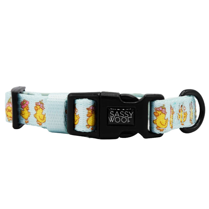 The Sassy Woof Dog Four Piece Bundle - Good Duck, Babe! includes a light blue adjustable collar with yellow ducks in flower crowns, a black plastic buckle, and D-ring—ideal for matching with an adjustable harness for your growing pup.