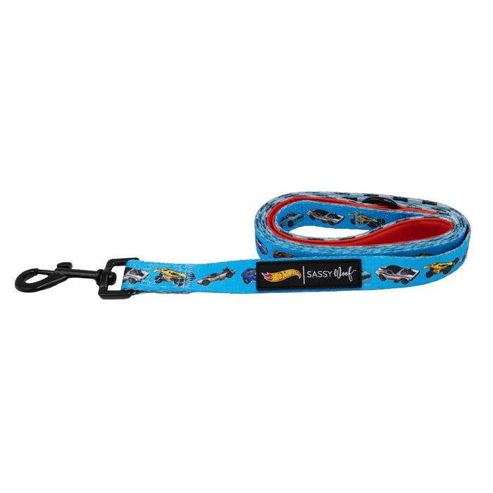 The Sassy Woof Dog Leash - Hot Wheels™ is blue with a black clasp, colorful car prints, and a bold red inner lining—ideal for racing fans. Rolled up design shows off the vibrant style and “Sassy Woof” label.