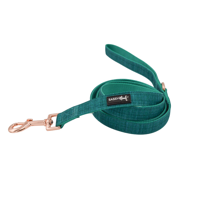 A rolled-up teal dog leash with a rose gold clasp and a “SASSY WOOF” tag, displayed on white—perfect to pair with your Sassy Woof Dog Two Piece Bundle - Napa for stylish walks.
