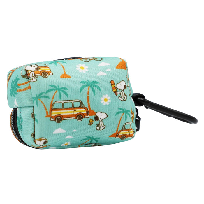 The Sassy Woof Dog Waste Bag Holder - Peanuts™ Road Tripping is a small teal neoprene holder with a black clip, featuring cartoon Snoopy, surfboards, palm trees, orange cars, and scattered white flowers—a playful accessory for dog adventures.