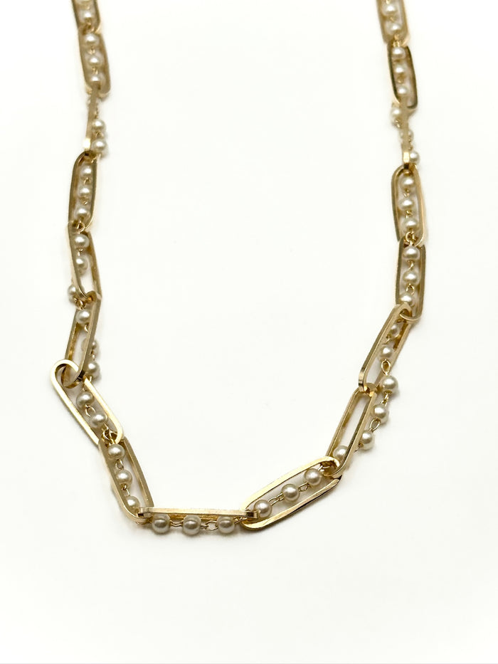 Gold chain necklace with embedded pearls on a white background