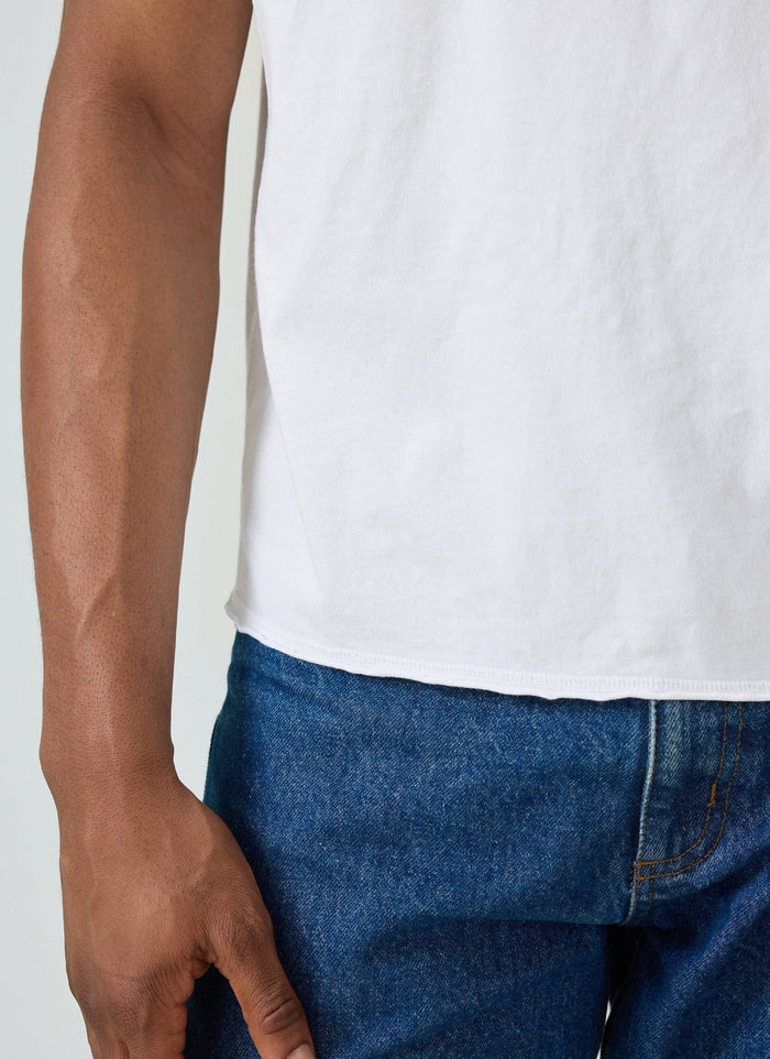Close up of a model wearing the white Champion x Percival t-shirt, showing the raw hem detail against blue jeans.