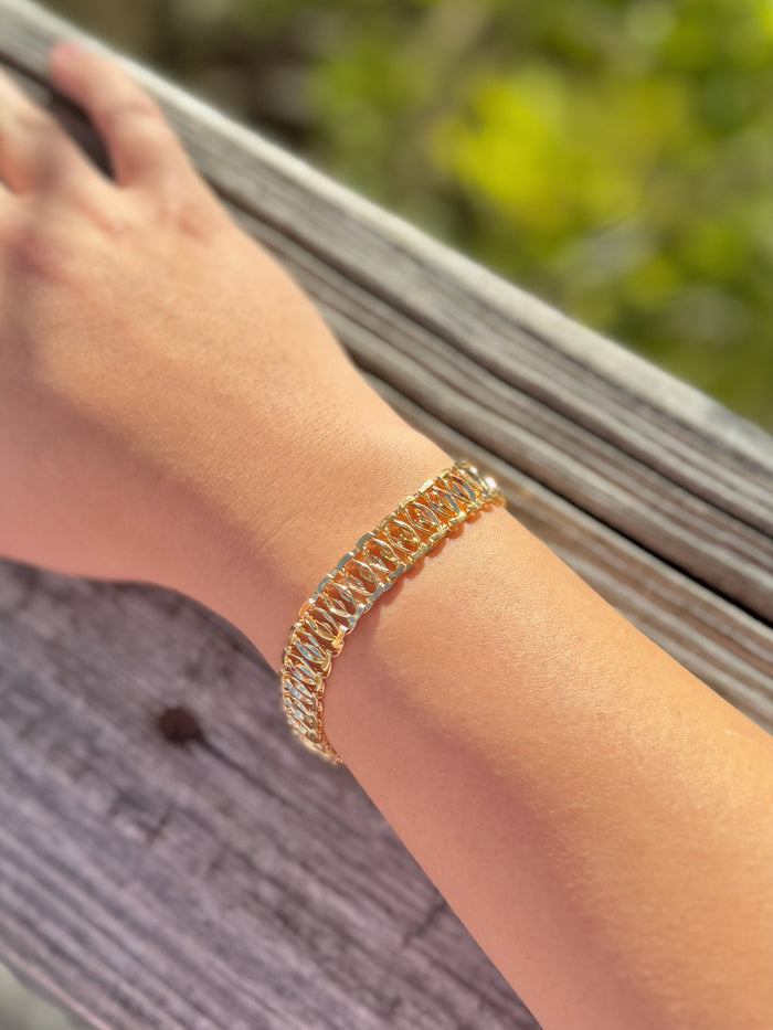 gold bracelet on a wrist with a blurred natural background