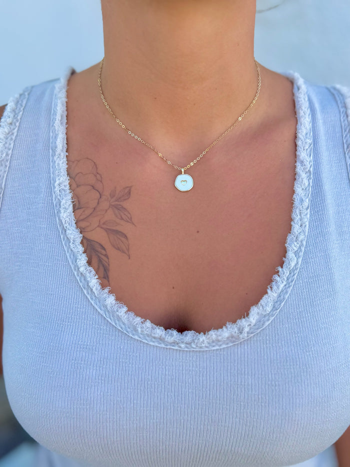 Necklace with a gold chain and pendant featuring a gold heart design being worn