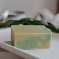 Green and yellow soap bar on a white plate with a blurred background