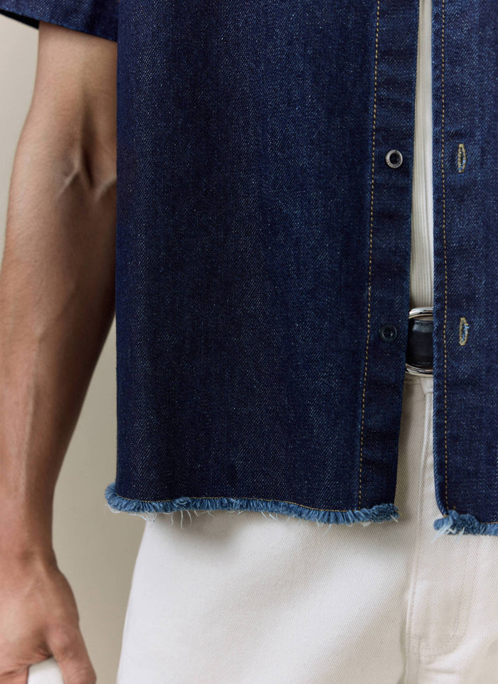 Close-up of the Percival Harley Denim Cropped Boxy Shirt in dark indigo, showing the raw frayed hem and cotton texture.