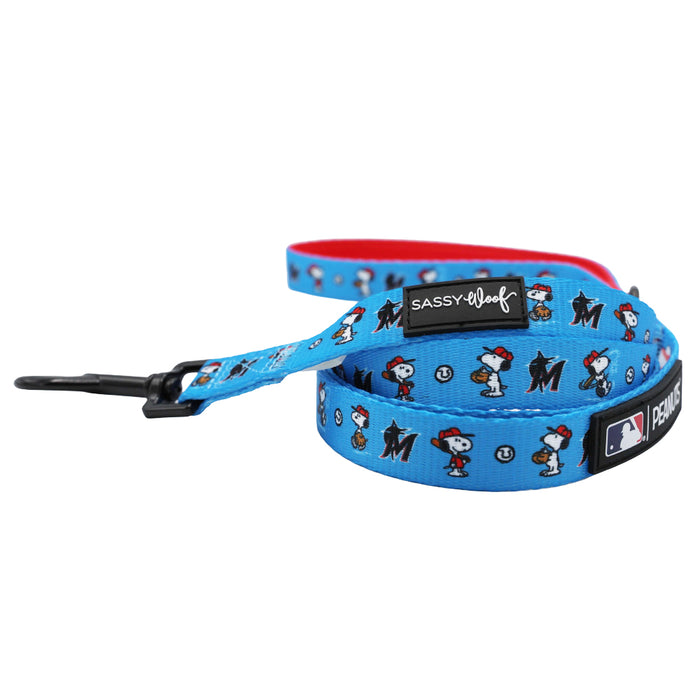 The Sassy Woof Harness Three Piece Bundle - MLB™ x Peanuts™ Miami Marlins™ features a blue dog leash with Snoopy, baseballs, and team logos, plus a black clasp and brand tag. Pairs perfectly with an adjustable harness for comfort and style.