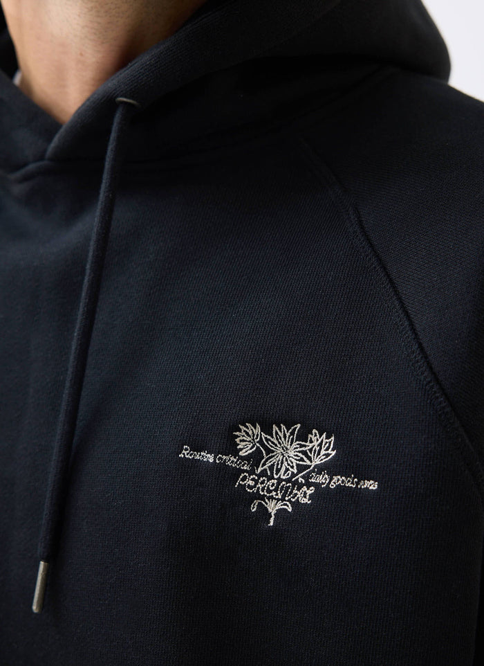 A close-up of the intricate floral embroidery on the chest of the black Heritage 90's Raglan Hoodie from Percival.