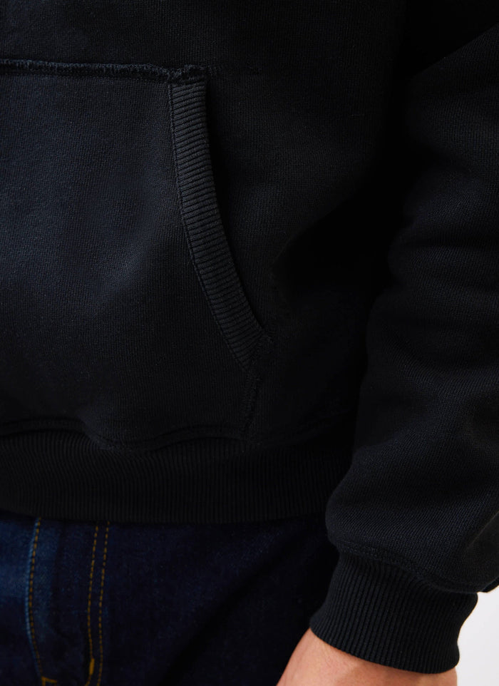 A close-up of the Percival Heritage 90's Raglan Hoodie in black, showing the kangaroo pocket and ribbed cuff detail.