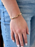 Gold bracelet on a wrist with a blurred denim background