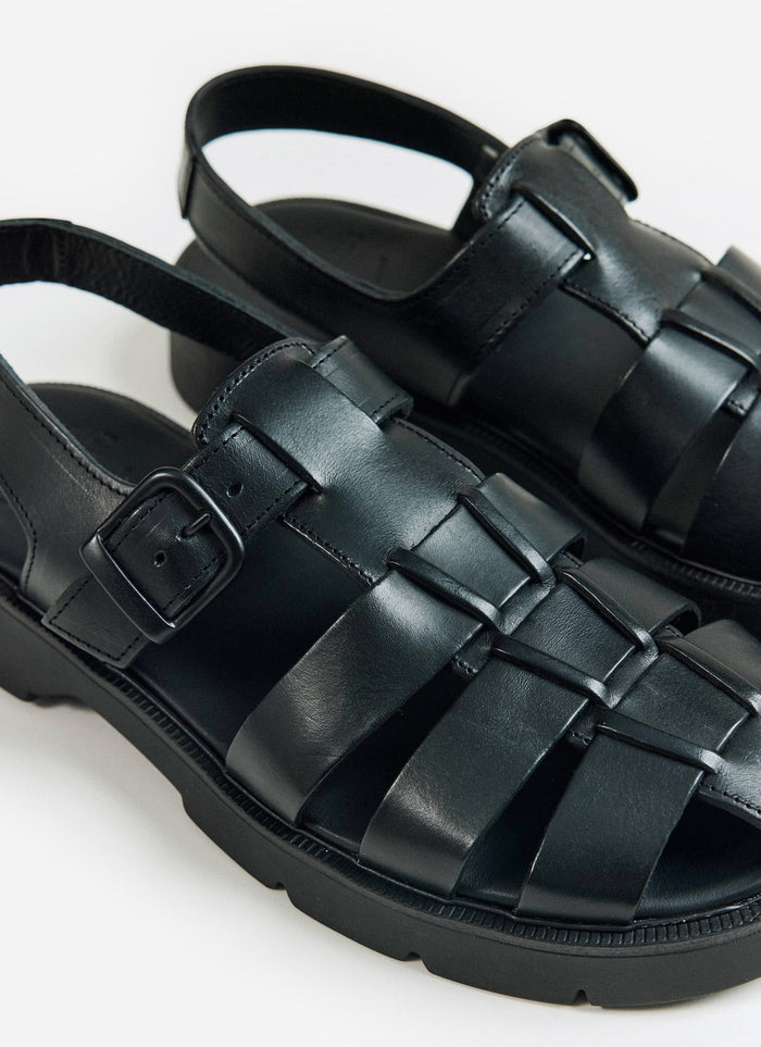 A close-up of the black Kleman Babord VGT leather fisherman sandals from Percival, showing the buckle and woven straps.