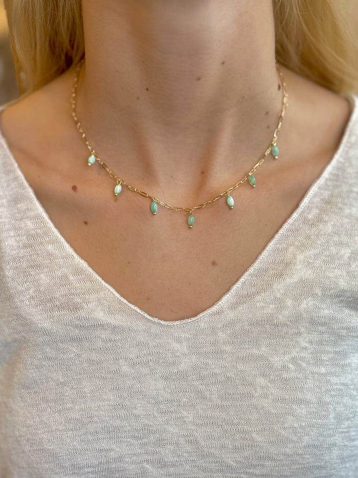 Model wearing The Lila Necklace – gold chain with seafoam green beads styled with a white knit top