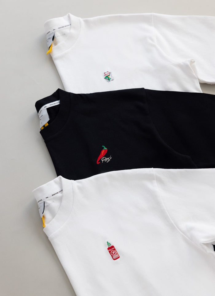 The exclusive black Percival Loyalty T-shirt with chilli embroidery, displayed with two other tees from the collection.