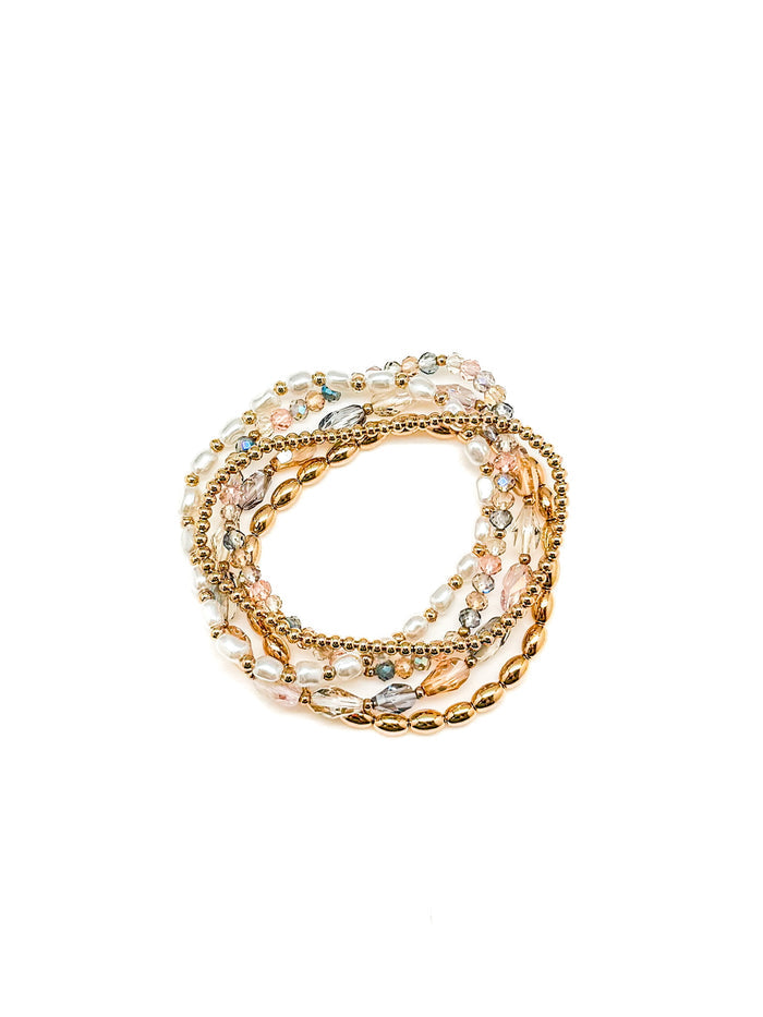 Set of gold and rose gold bracelets with gemstones on a white background