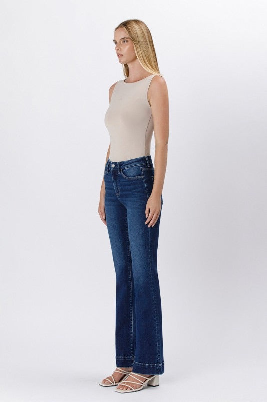 Side view of model in dark wash bootcut jeans and white strappy heels.