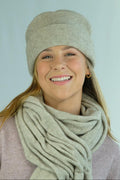 Woman wearing a beige knit hat and scarf against a light blue background