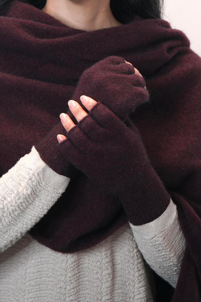 A pair of merino fingerless gloves in red, being worn by a person.