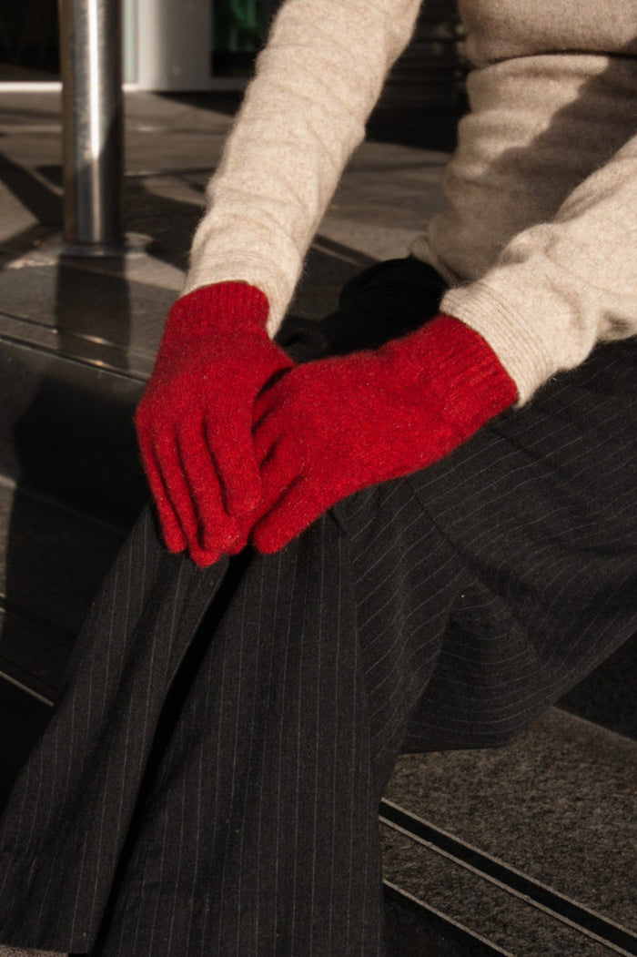 Person wearing red gloves sitting on steps outdoors