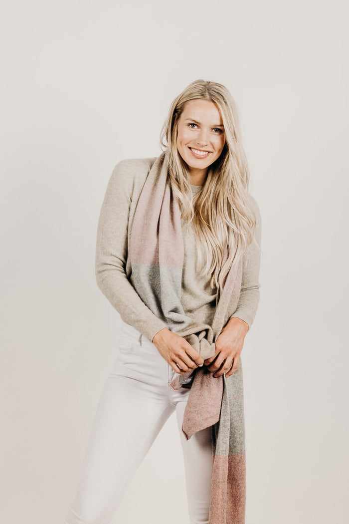 Woman wearing a light gray sweater and scarf against a plain background