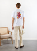 A male model, seen from behind, wears the white Octo Oversized T-shirt by Percival, showcasing the red octopus chef print.