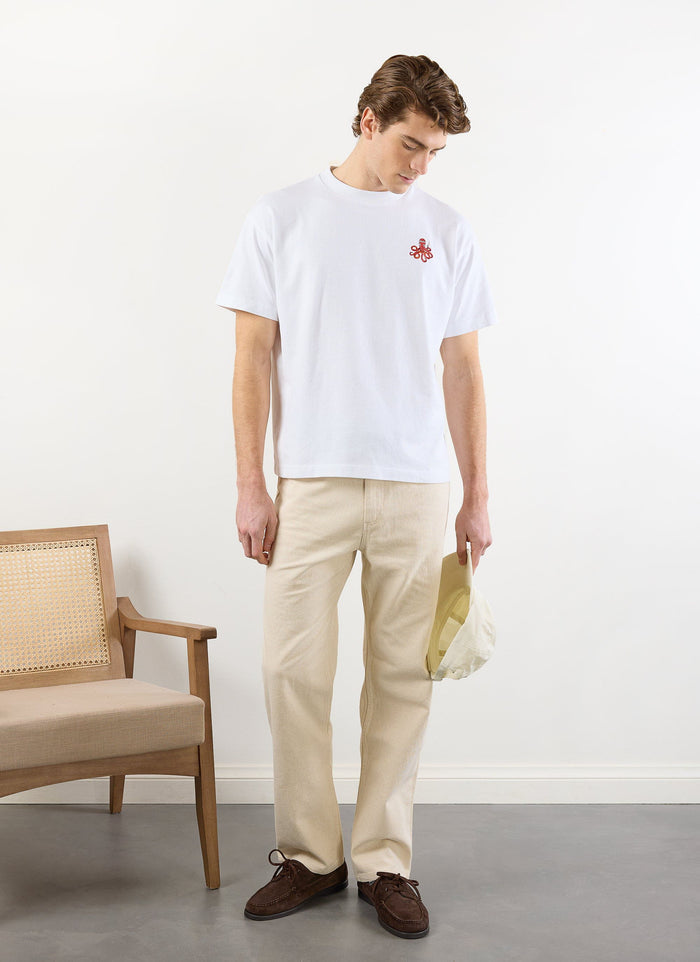 A model stands wearing the white Percival Octo Oversized T Shirt, which features a small red embroidered octopus.