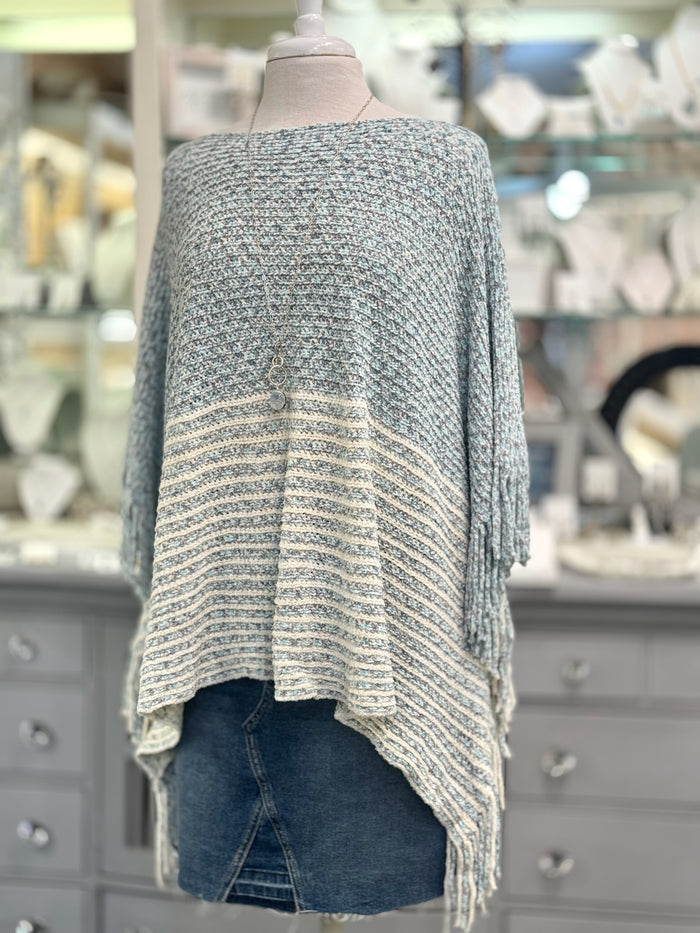 Knitted poncho on a mannequin with a blurred store background