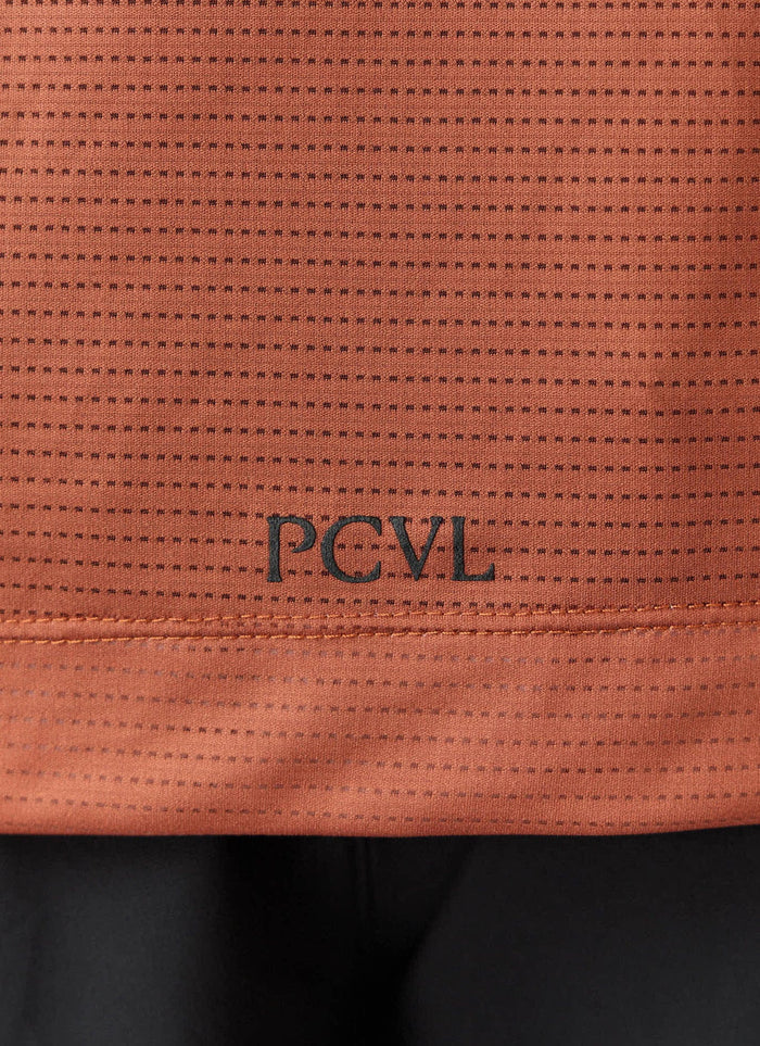 A close-up of the Percival PCVL Printed Performance Top in rust, showing the black printed logo and breathable fabric.