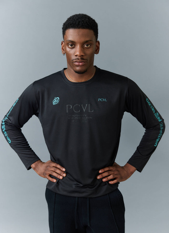 A model wears the Percival PCVL Long Sleeve Printed Performance Top in black, showing the chest and sleeve graphics.