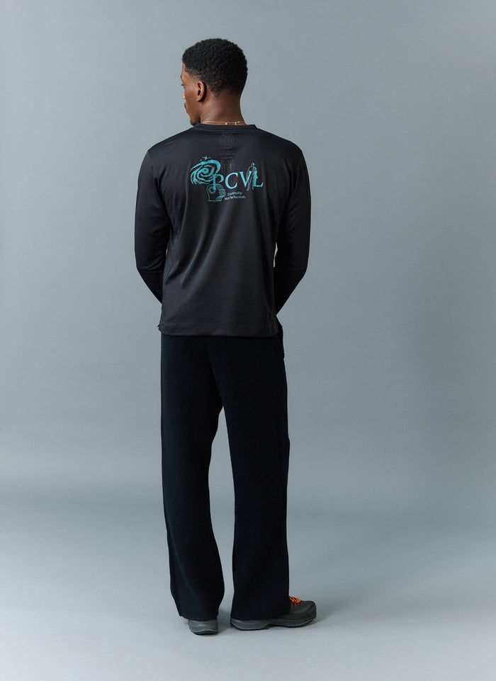 Back view of a model wearing the PCVL Long Sleeve Printed Performance Top in black by Percival, showing the blue graphic.