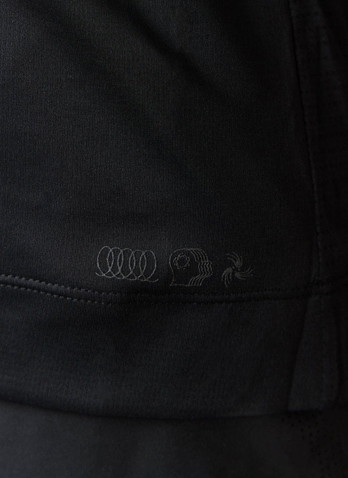 A close-up of the tonal PCVL artwork on the hem of the black Performance Vest by Percival.