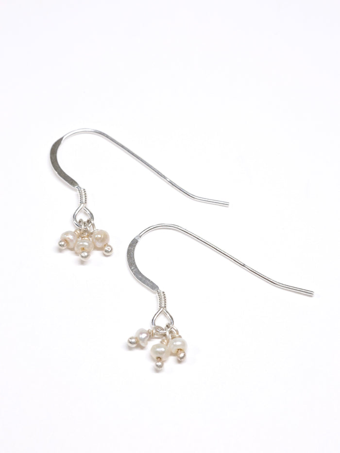 Silver earrings with small pearls on a white background