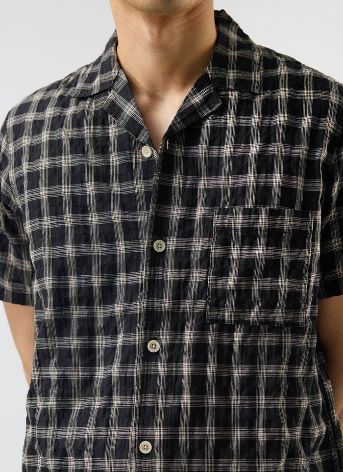 A close-up of a model wearing the Percival Ryco Cuban Collar Shirt in a black and white cotton check.